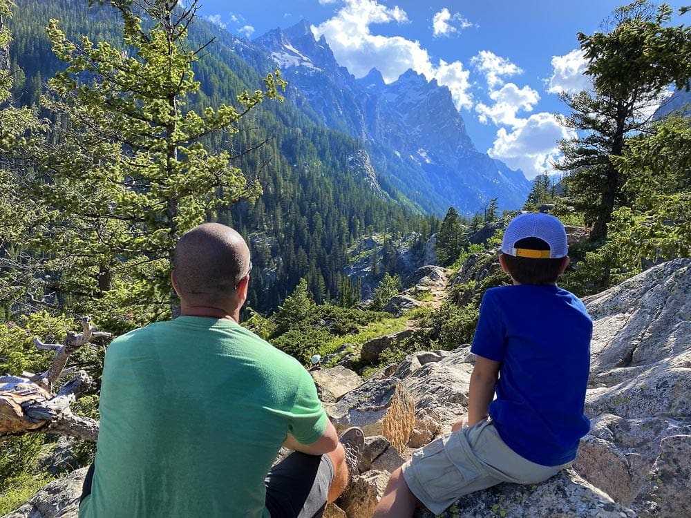 Father and son sit looking out onto the Grand Tetons, one of the best places for families in the U.S.