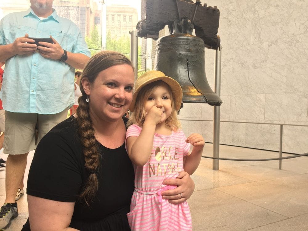 Mother and child stand in front of the Liberty Bell in Philadelphia, one of the best Philadelphia attractions for families.