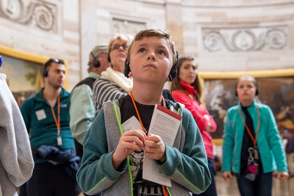 Young boy listens to an audio tour guide on a museum tour.