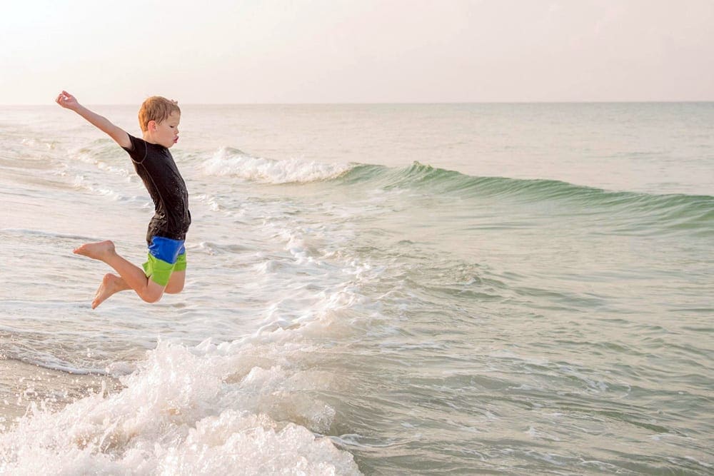 Boy jumps into the water at Panama City, one of the best Florida beaches for families.