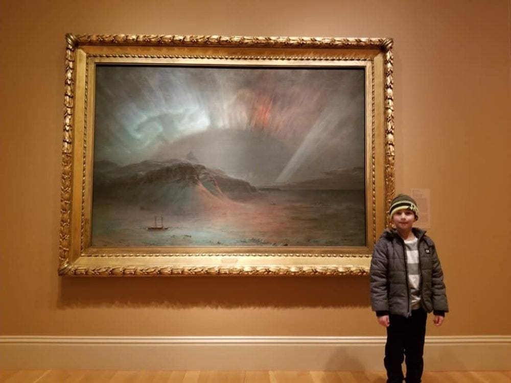 A young boy stands in front of a landscape painting at the Portrait Gallery in Washington D.C. One of the 9 Things to Do Washington DC with Kids.