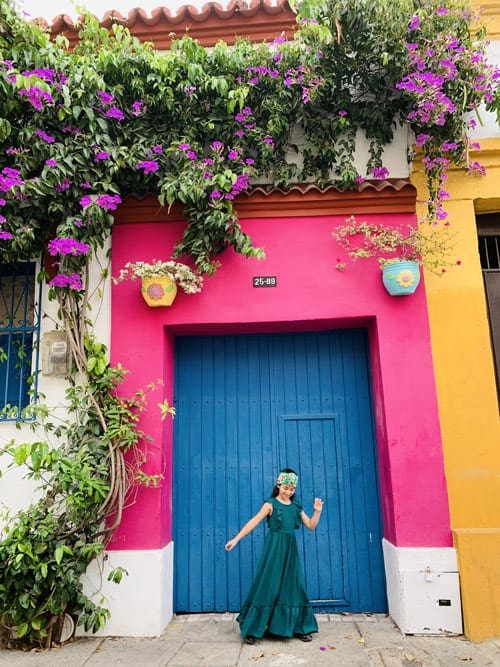 Girl dancing in front of a colorful door in Cartagena Colombia
