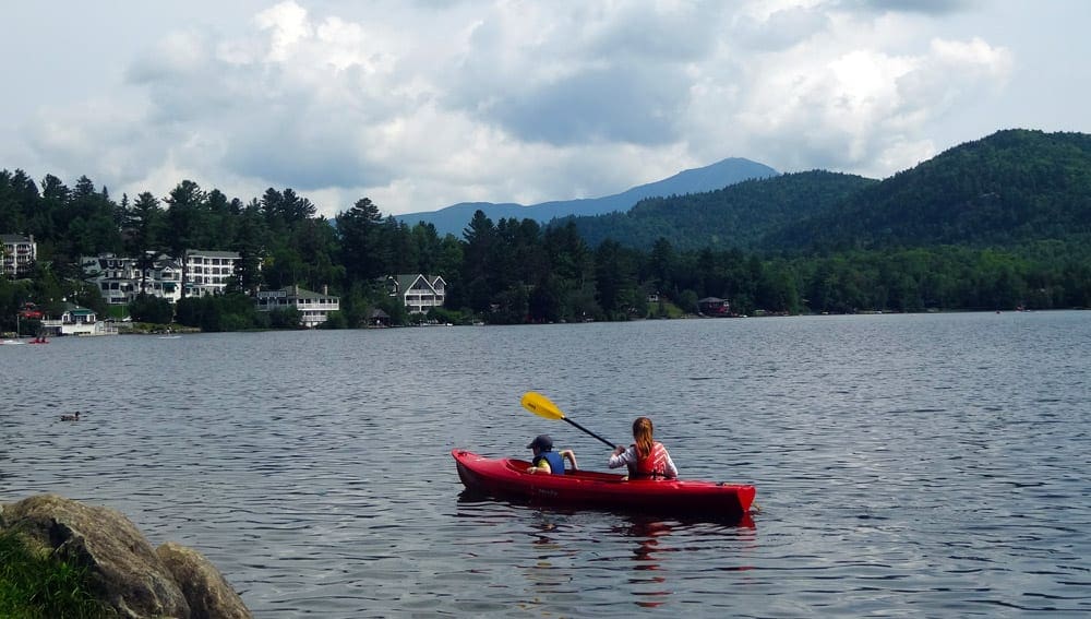 Mom and a son on a kayak in Lake Placid NY, one of the Best US Lakes to Visit with your Family this Summer.