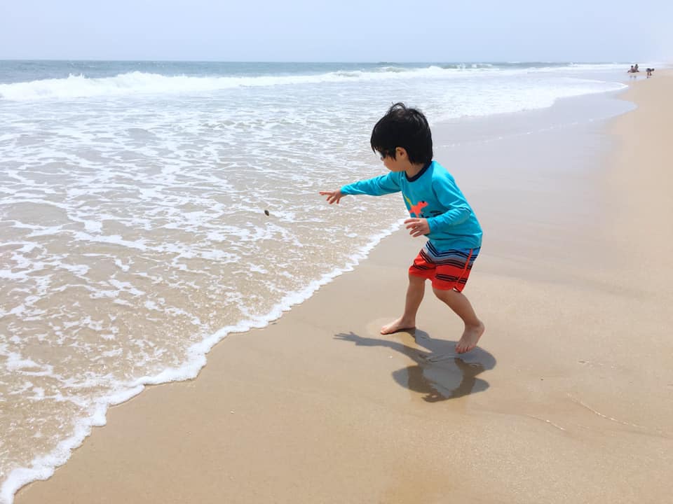 Little boy plays on the beach in The Hamptons, one of the best East Coast summer destinations for families.