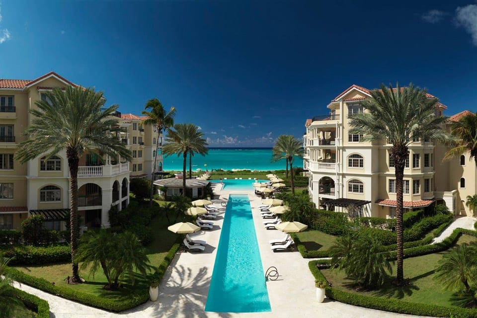 A long pool rests between large resort buildings, and leads to the beach access at The Somerset On Grace Bay.