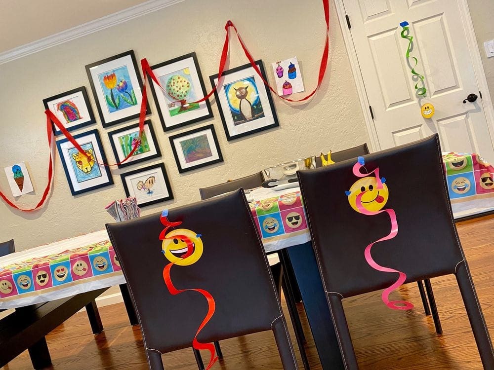 Decorations hung around a large dining room including streamers and place settings, all with an Emoji theme.