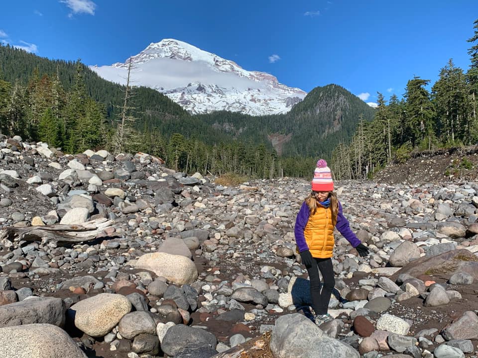 A young girls hikes across a field of rocks in Mt. Rainier National Park.