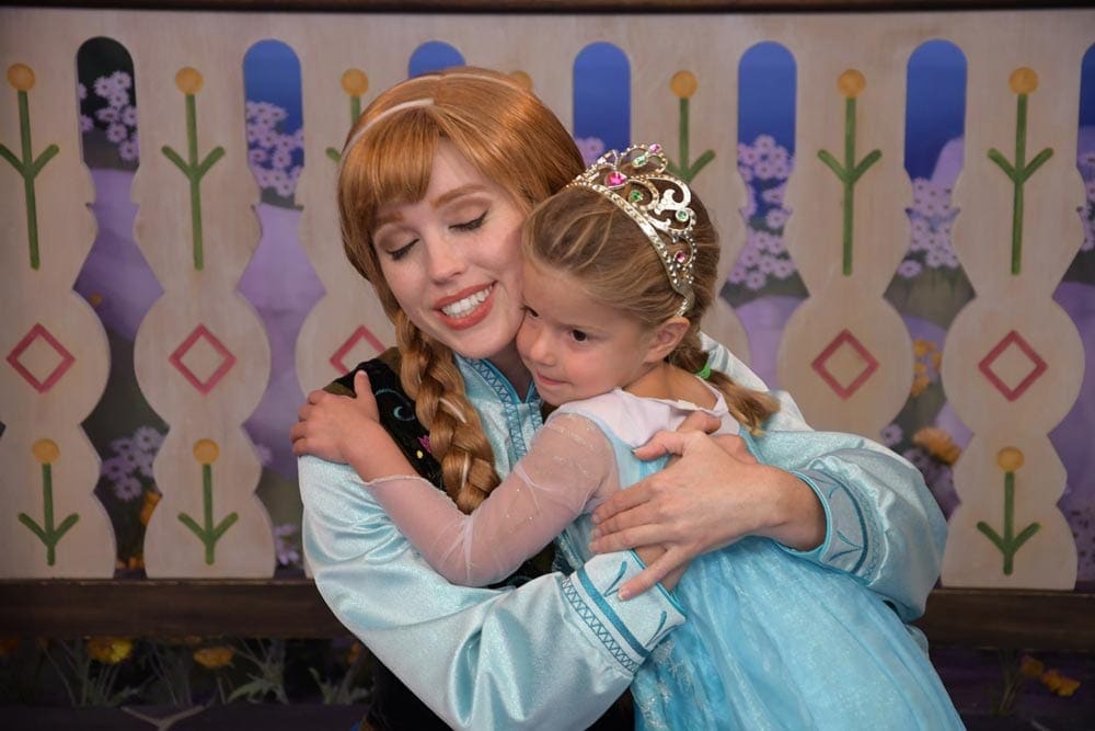 Girl in princess dress and tiara hugging the Frozen character, Anna, at Disney World, one of the vacations to plan a year in advance