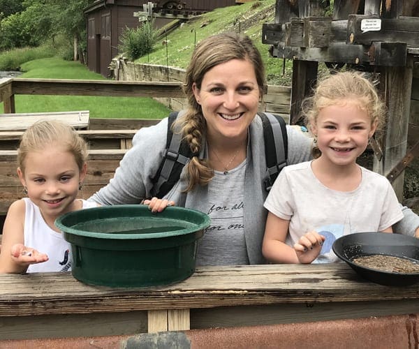 A mom and two young daughters sit smiling as they show off the gold they panned in South Dakota.