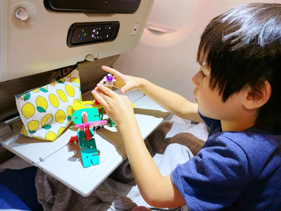 Small boy playing with toys on an airplane. Packing new toys is one of the best tips for traveling with a toddler.