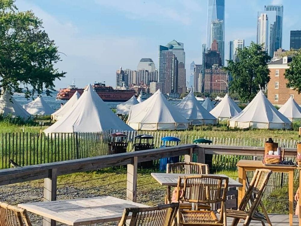 Several luxury tents stand in front of the New York City skylne, Your Guide To Family Glamping in Style