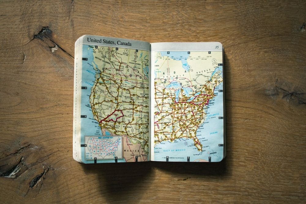 United States road map lays open on a wood table. Doing your reserach is our first Coronavirus Travel Tips For Families.