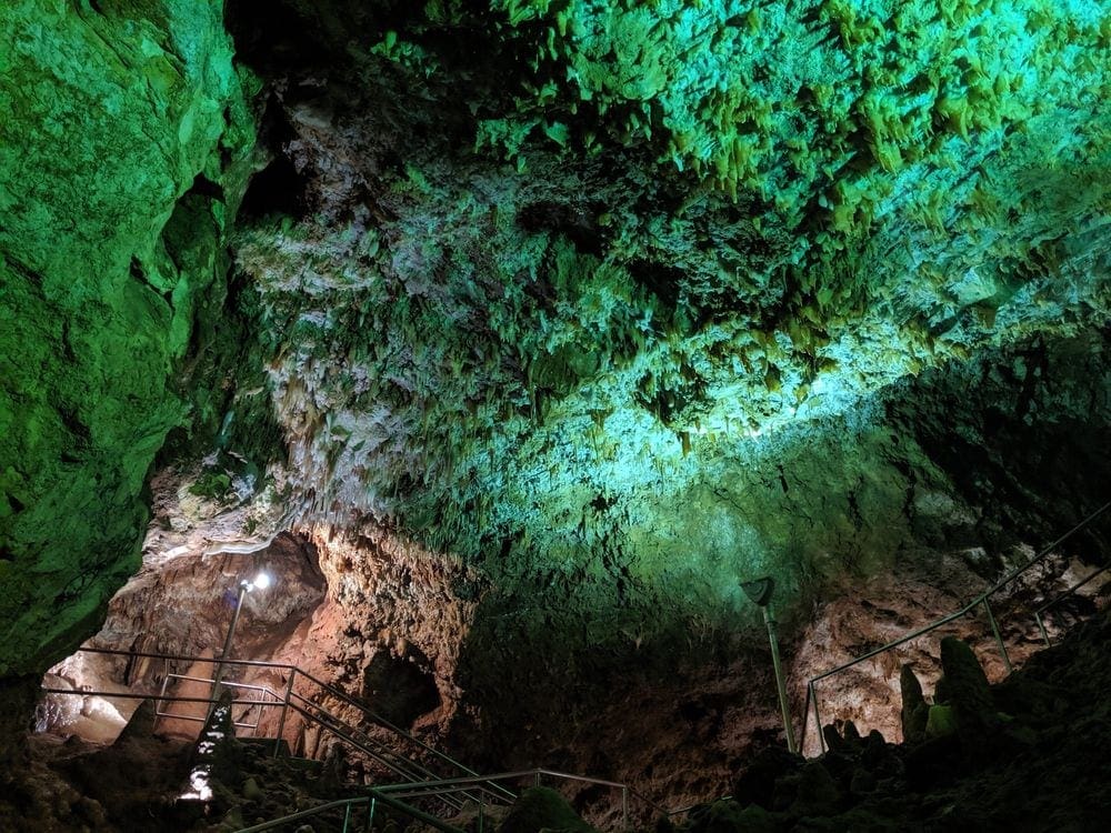 Inside Rushmore Cave, located at the Rush Mountain Adventure Park. Green lights shine on the ceiling of the cave. Families will love doing a cave tour on their Black Hills vacation with kids.