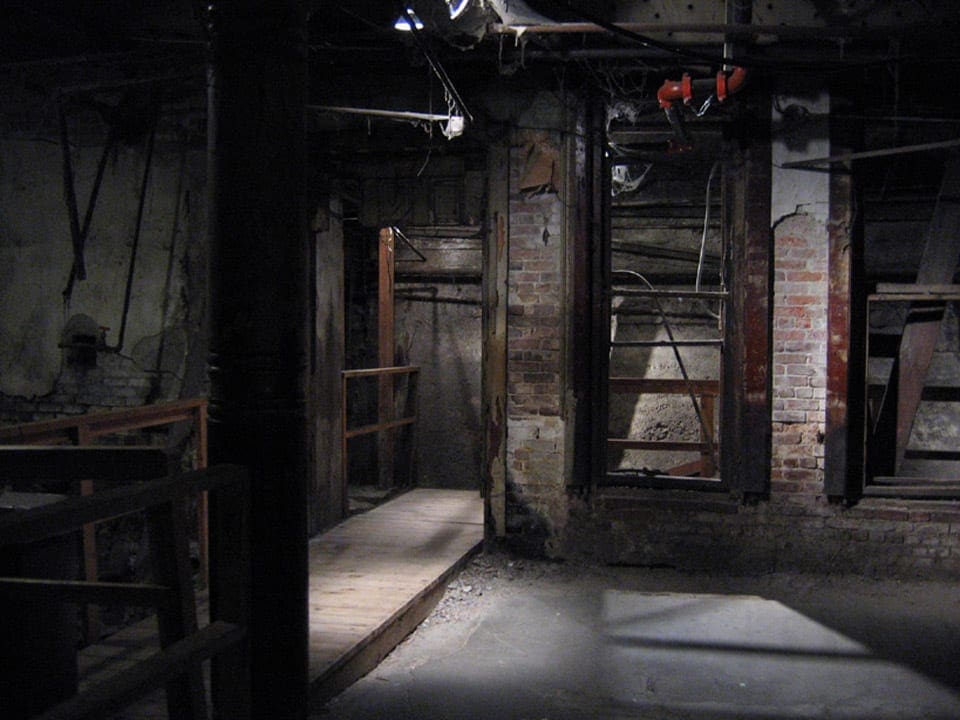 A view of one of the underground tunnels in Seattle Washington featuring pipes, brick, and dim lighting.