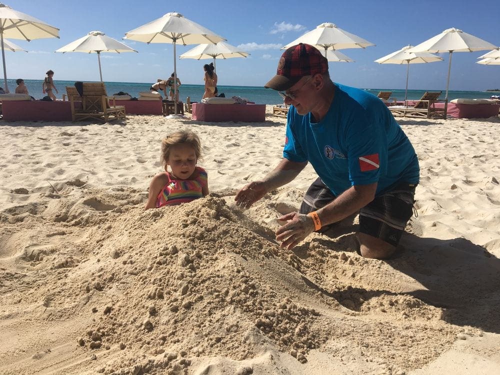 A grandfather burries his granddaughter in sands on a Cozumel beach.