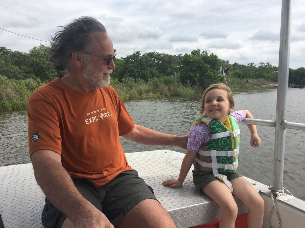 A grandfather smiles at his young granddaughter who is smiling back up at him while riding a small boat in a bayou near New Orleans. Strengthening family bonds is huge benefit of multigenerational travel