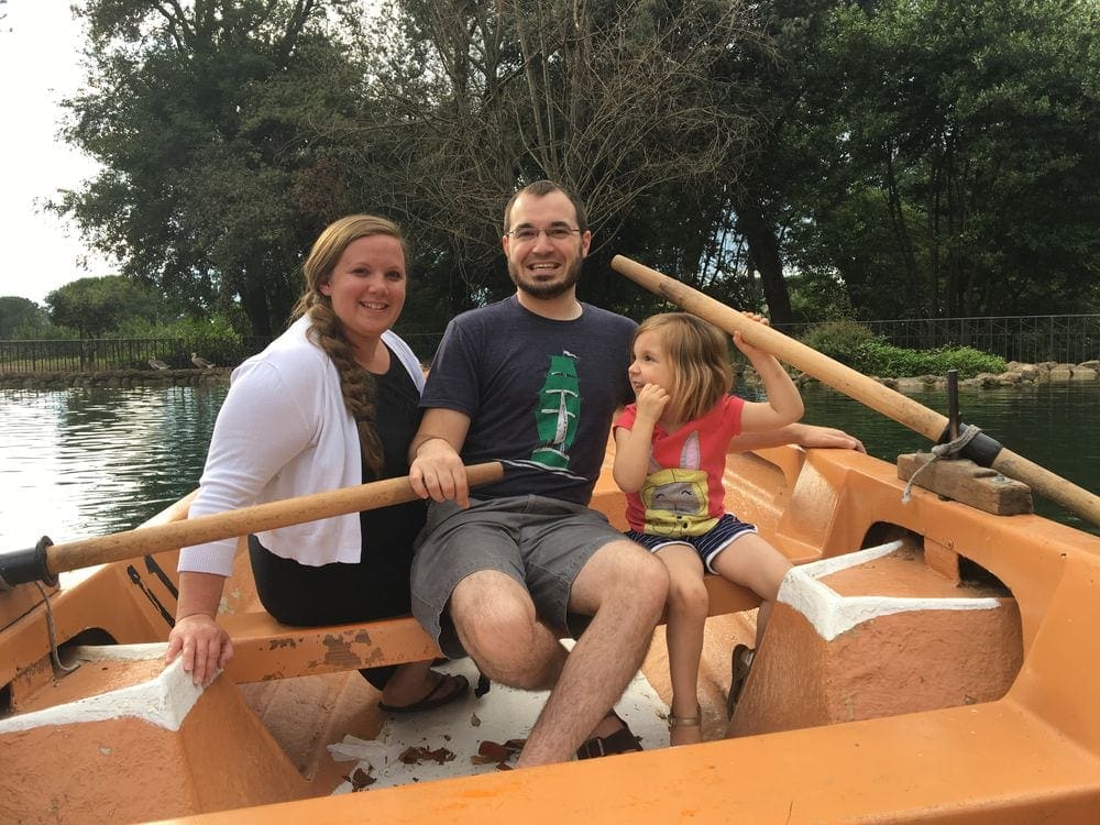 A family of three sits smiling in a paddle boat on the pond in the Borghese Villa in Rome, Italy. Making family memories is truly one of the best benefits of traveling with kids.
