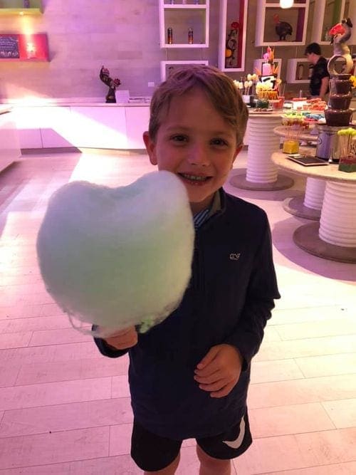 A young boy proudly holds his blue cotten candy within the Hyatt Ziva Cancun.