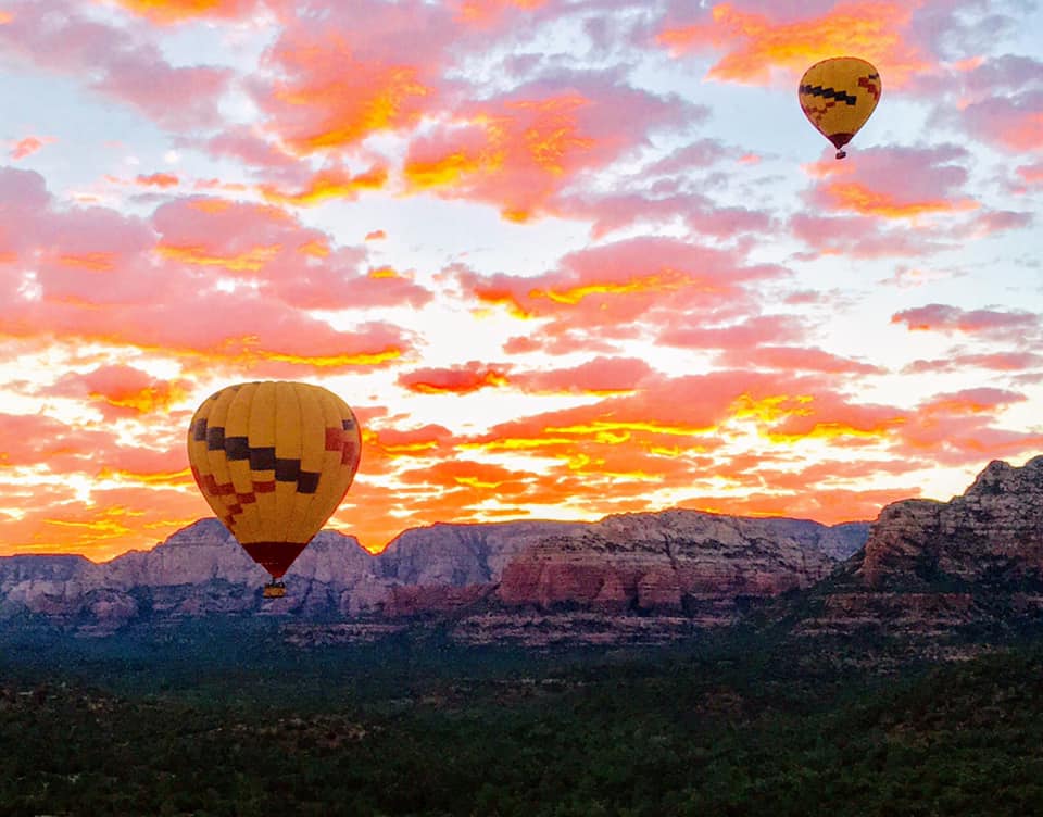 A hot air balloon rising above a beautiful, orange and pink sunset in Sedona, one of the best Moms’ Getaways or Girls’ Trip Ideas.