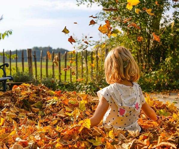 Girl playing in leave in fall in Colorado