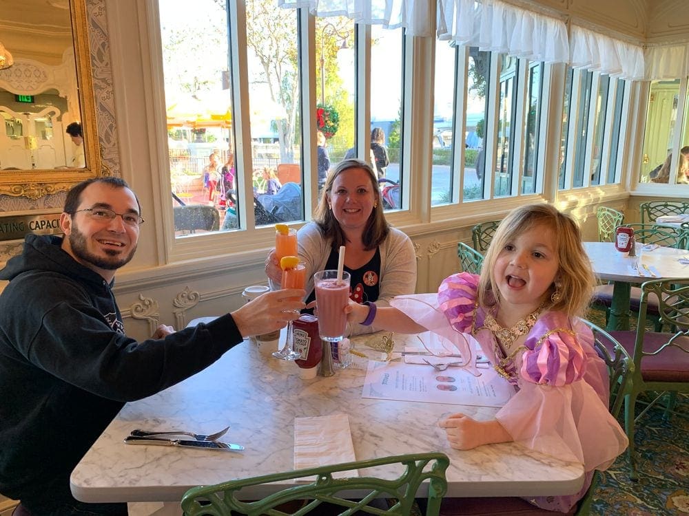 A family of three does a cheers with smoothies inside a restaurant at Walt Disney World.