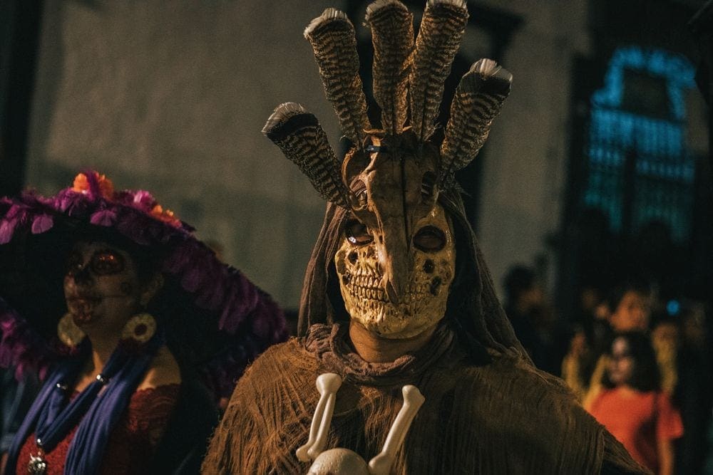 A close up of someone dressed in a cultural mask during a Day of the Dead parade in Oaxaca, Mexico, one of the best places to go for Halloween.