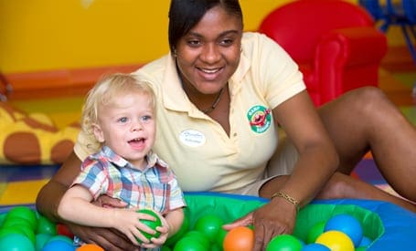 A childcare provider sits laughing with a young child at the kids club at Beachs Turks & Caicos.