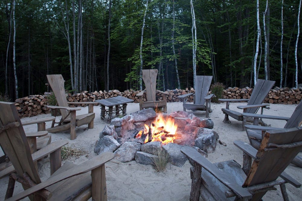 Several chairs circle a fire pit on-site at Hidden Pond, one of the best Maine hotels for families.
