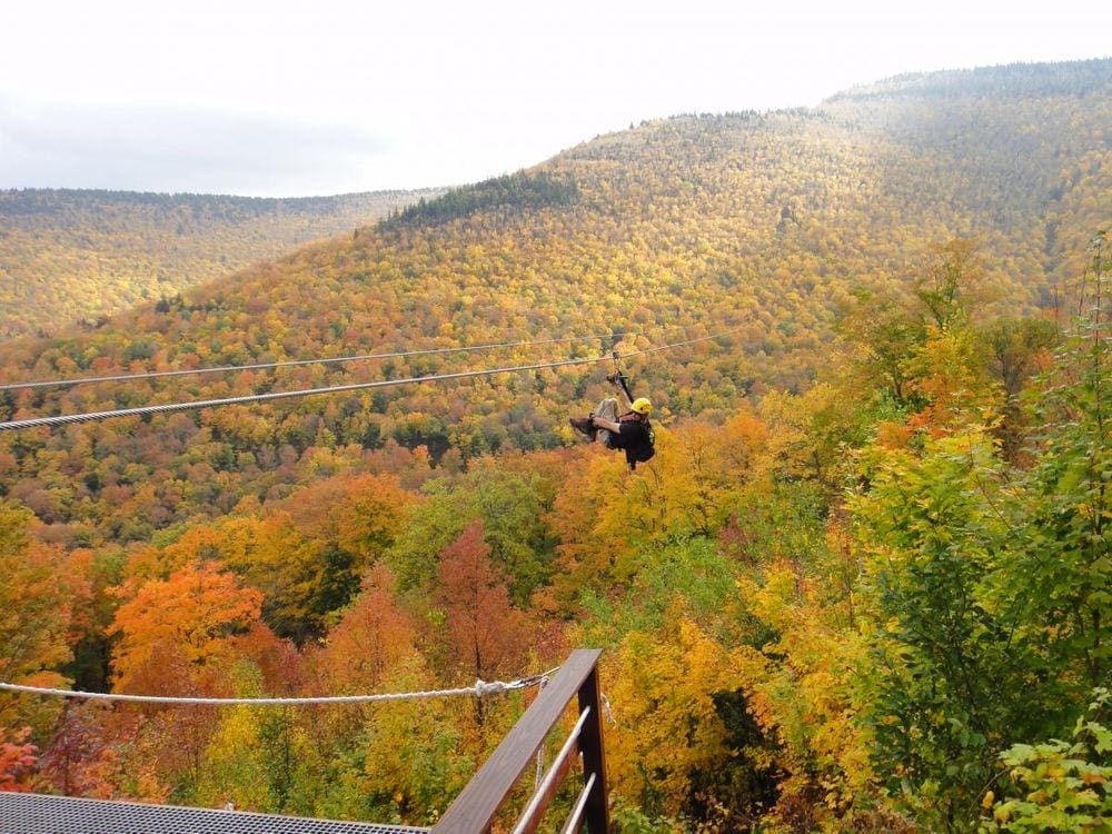 A man ziplines amoung stunning fall foliage near NYC at Hunter Mountain.