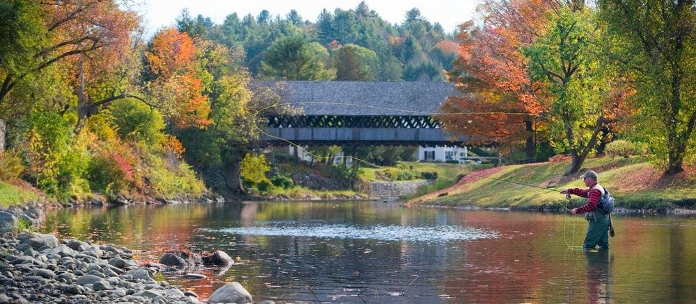 A man fly fishes in a quiet river on a stunning fall day at the Woodstock Inn & Resort, one of the best weekend getaways near Boston for families.