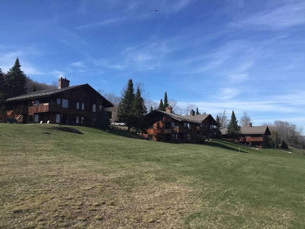 Several buildings of the Trappy Family Lodge lay beyond an expansive greenspace.