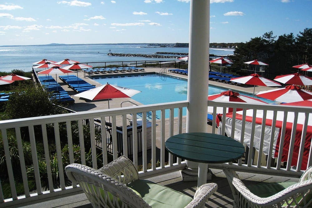 Nestled amongst red and white umbrellas is the pristine outdoor pool at The Colony Hotel, one of the best Maine hotels for families.