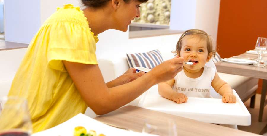 A baby club staff member is feeding a small baby at Club Med Punta Cana.
