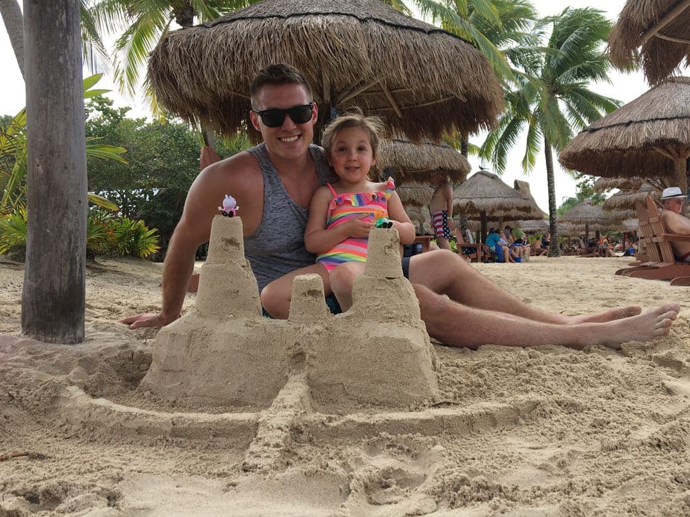 An uncle sits with his niece building a sand castle at Chankanaab, a beach club in Cozumel, Mexico.