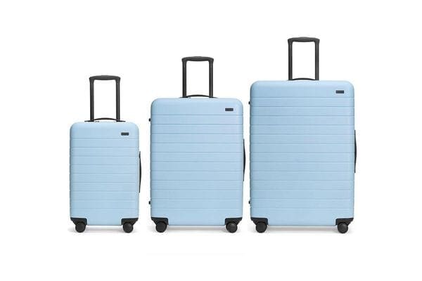 Product shot of Away luggage in powder blue, featuring three different sizes from carry-on to large.