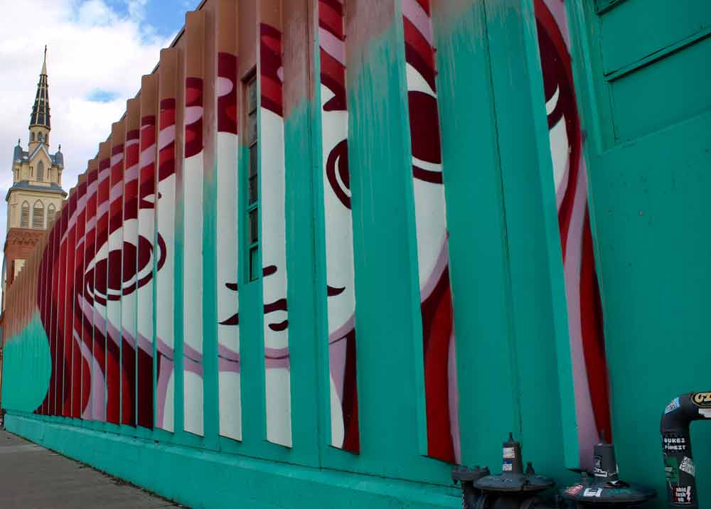 A street art mural of a girl's face using hues of reds and green.