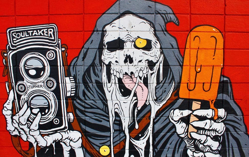 A Denver mural features a large painting of Death holding an orange popsicle and antique camera.