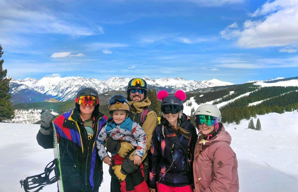 A family of five stands in the snow at Beaver Creek wearing helmets, goggles, and other snowgear.
