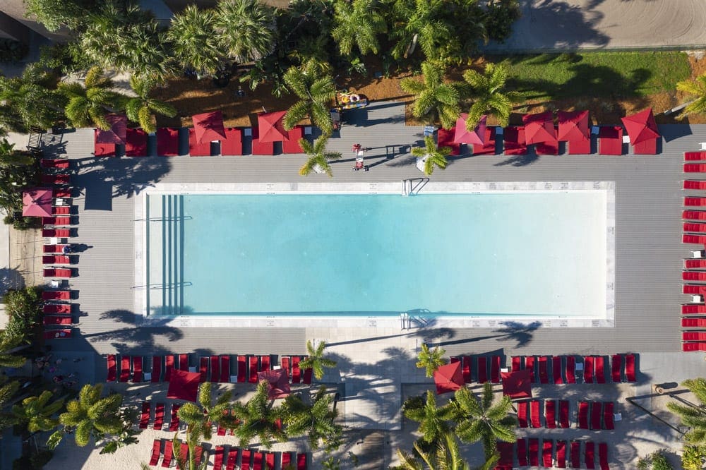 An aerial view of a large pool surrounded by red umbrellas at Club Med Sandpiper, one of the best family resorts in Florida.