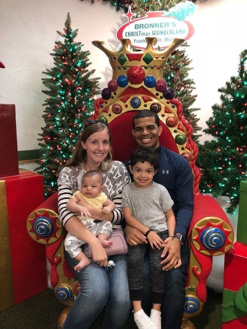 A family of four sits in a large Christmas throne at Bronner's CHRISTmas Wonderland in Frankenmuth, Michigan, one of the most magical Christmas towns for families.