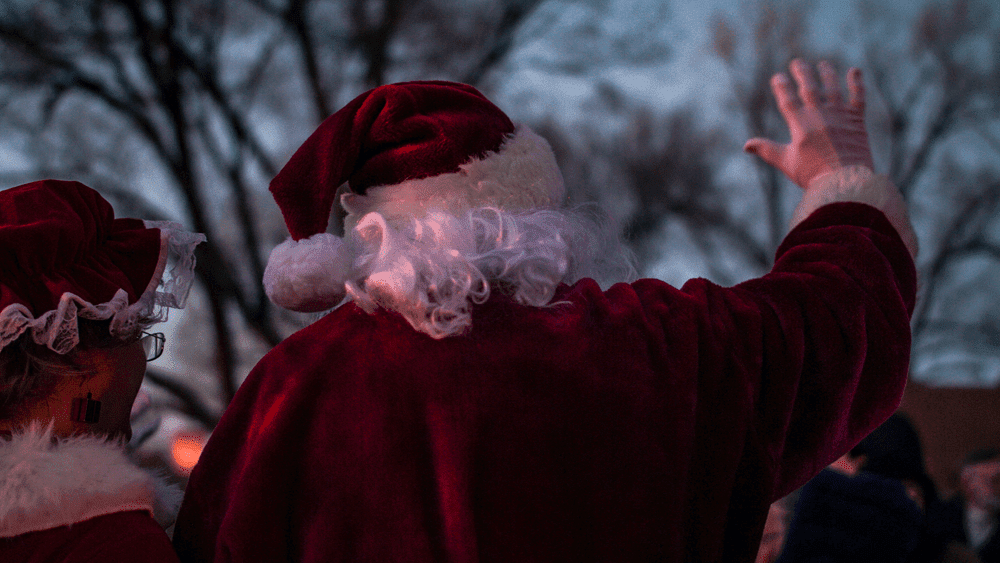 Mrs. Clause and Santa wave to a crowd during a parade in Taos, New Mexico, one of the most magical Christmas towns for families.