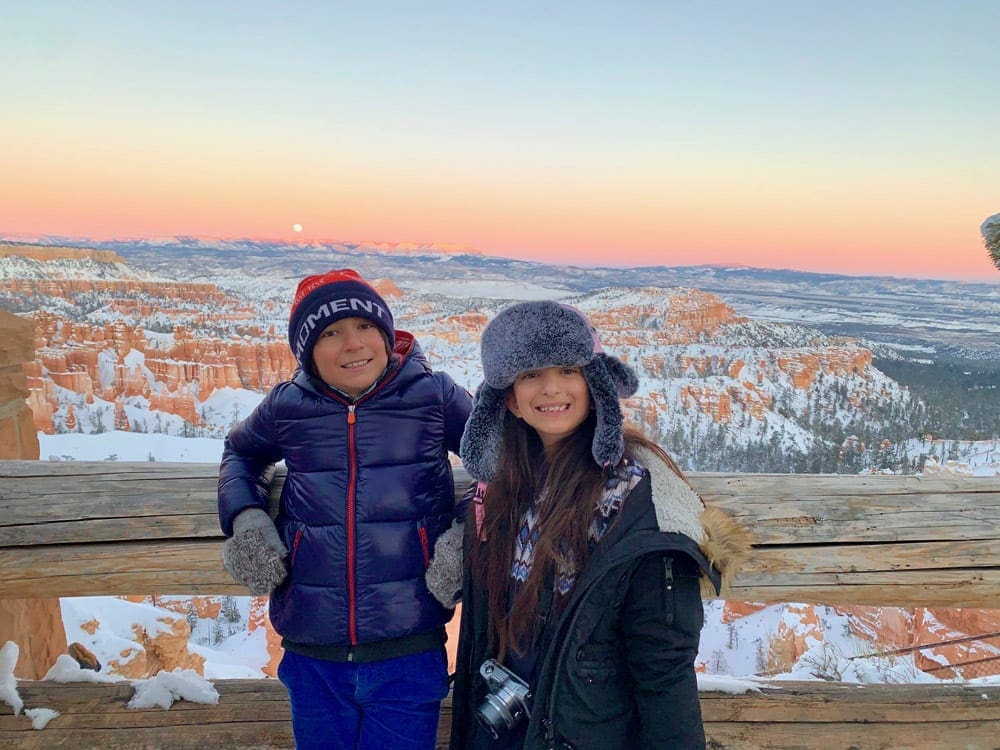 A boy and a girl posting in front of a beautiful sunset at Bryce National Park