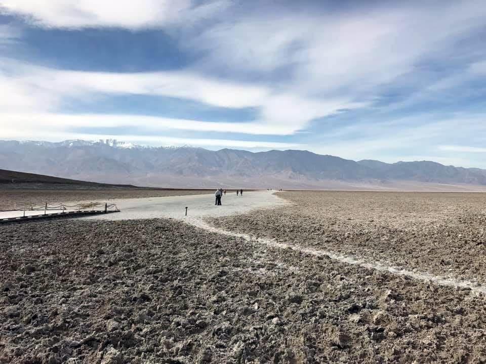 The sparse landscape of Death Valley National Park, one of the best national parks in Winter with kids, with some hikers in the distance.