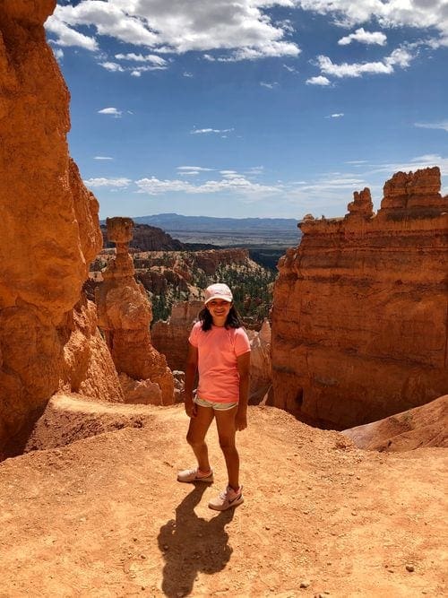 A young girl stands proudly on the Navajo Trail in Bryce Canyon National Park, one of the stops on this national park itinerary for families.