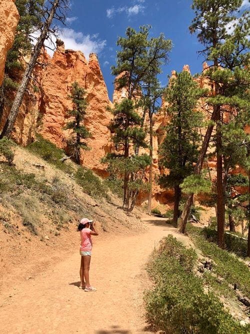 A young girl takes a picture along a hiking trail in Bryce Canyon National Park.