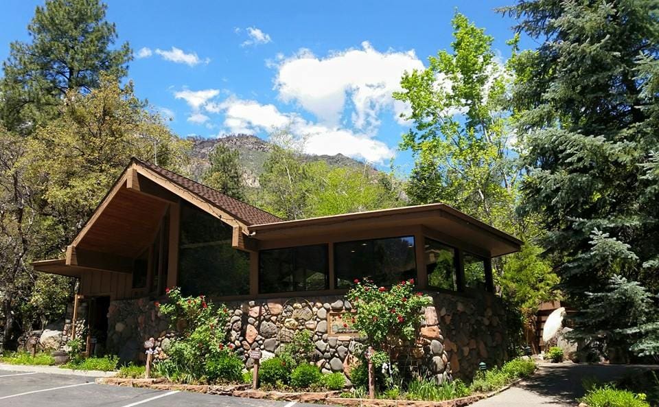 The entrance of Junipine Resort, one of the best hotels in Sedona for kids. Features lush greens and a blue sky.