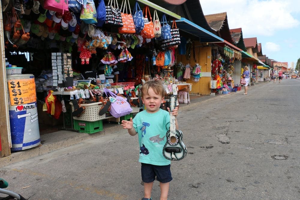 A young boy holds a souvenier guitar outside an open-air shop in Oranjestad.