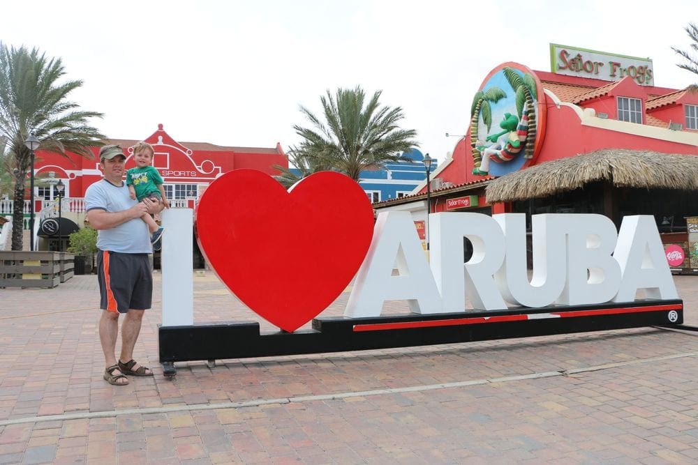 A dad holds his young son near a sign reading "I Heart Aruba" in Oranjestad.