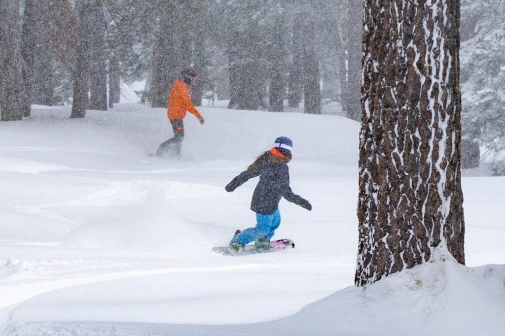 Two snowboarders curve down slopes at Northstart California Resort, one of the best ski resorts near Lake Tahoe for families.