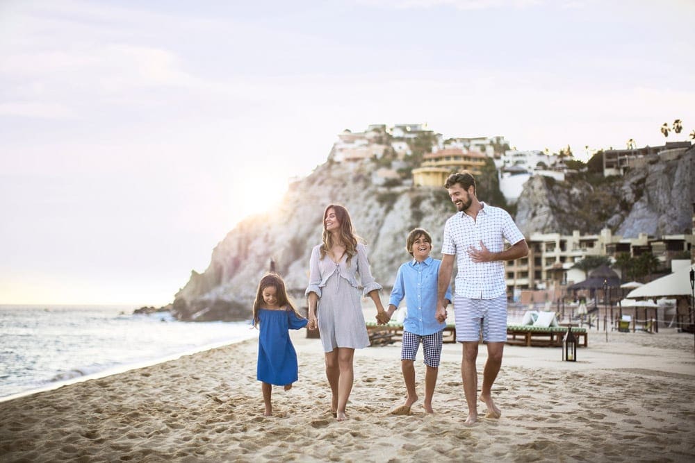 A family of four walks along the beach near Waldorf Astoria Los Cabos Pedregal Resort.